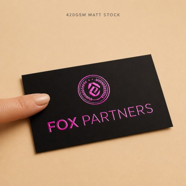 Fingertip touching the matt stock of a black magenta foil business card